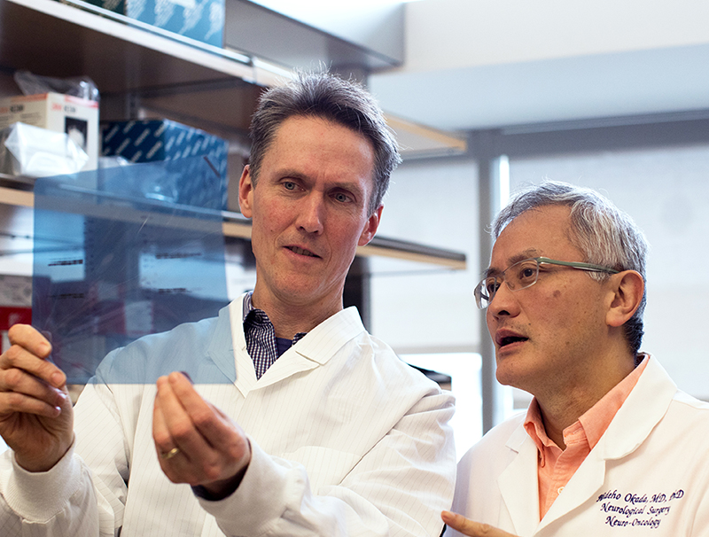 Joseph Costello, PhD and Hideho Okada, MD, PhD discuss results at the lab bench