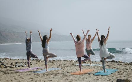 A class doing yoga at the beach on a cloudy day.