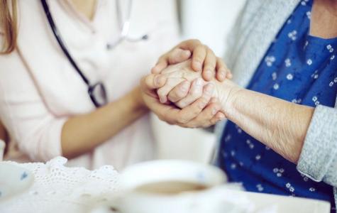 elderly woman holding hands with doctor