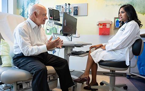 A patient sit in an exam chair, talking to their doctor.